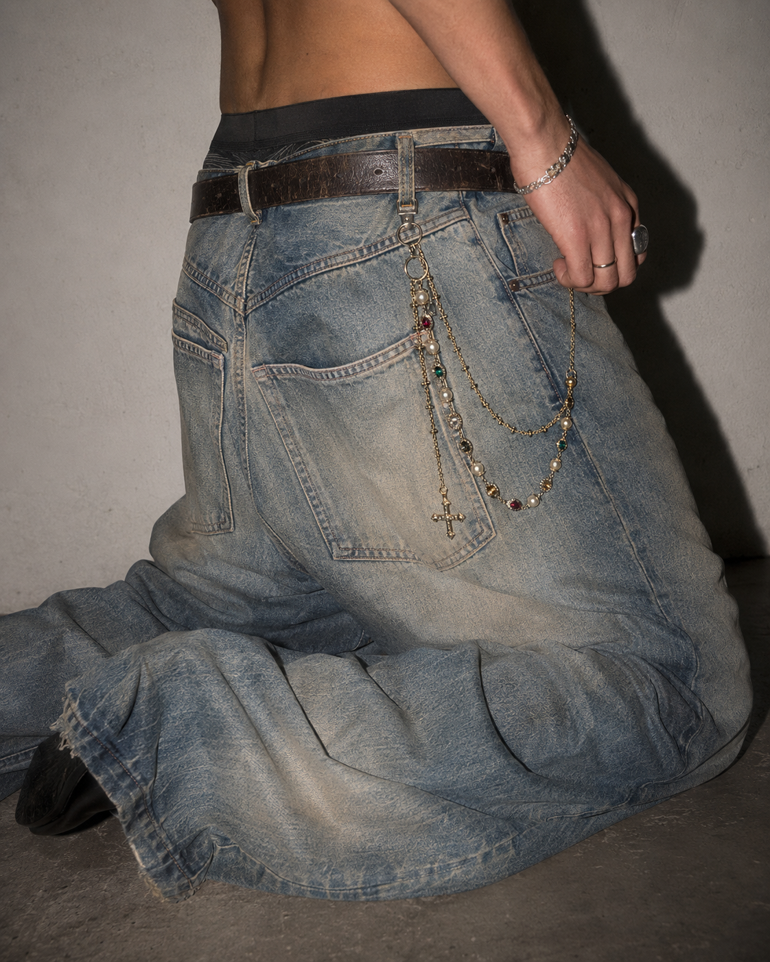 ADRN 02 Circle Gold pants chain worn laterally on oversized washed denim in a kneeling campaign shot